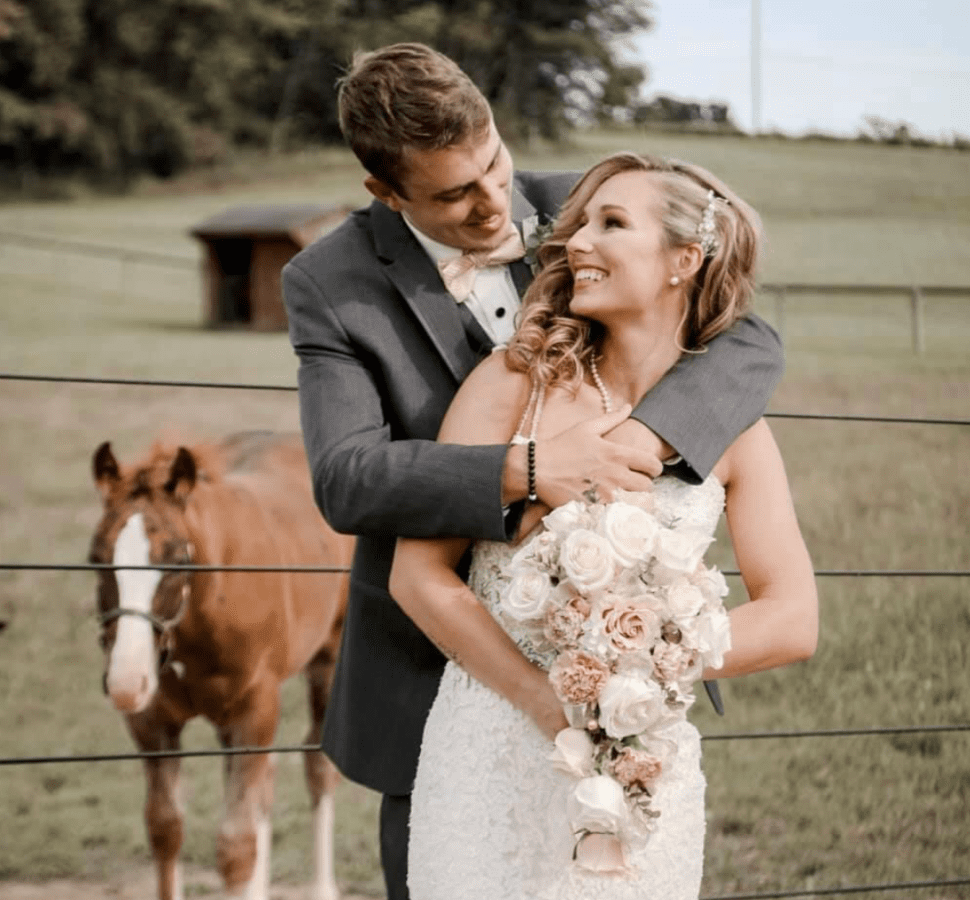 a bride and groom enjoy a rustic barn wedding venue in PA, embrace each other in front of a horse